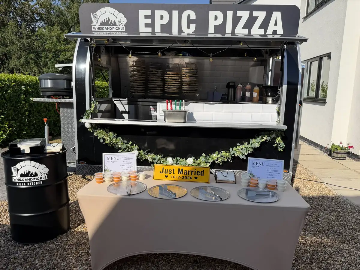 The trailer dressed for a wedding with eucalyptus garlands, a Just Married plate and serving platters laid out on a covered table.